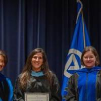 Provost Mili takes picture on stage with 2 faculty and certificates